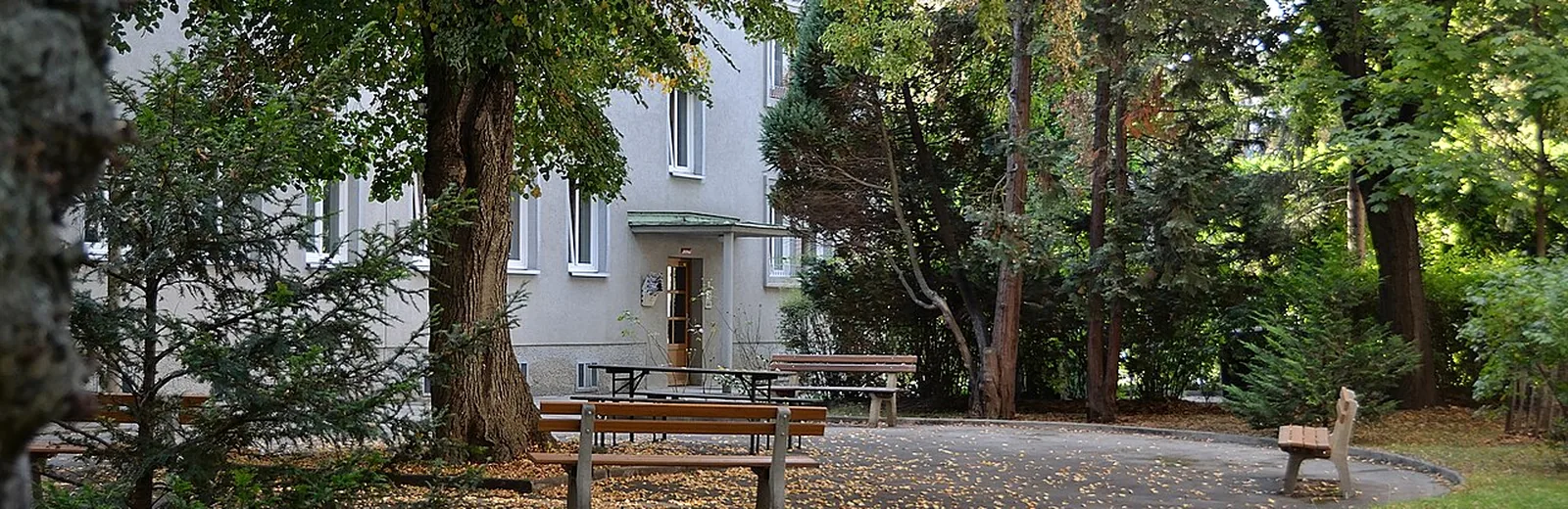 Begrünter Innenhof einer österreichischen Wohnanlage mit Hauseingang und Sitzbänken
