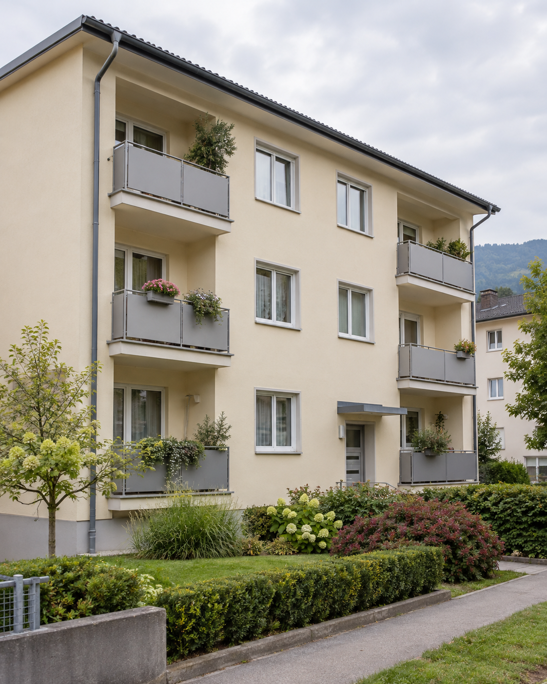 Kleines Mehrfamilienhaus mit Balkonen und bepflanztem Vorgarten